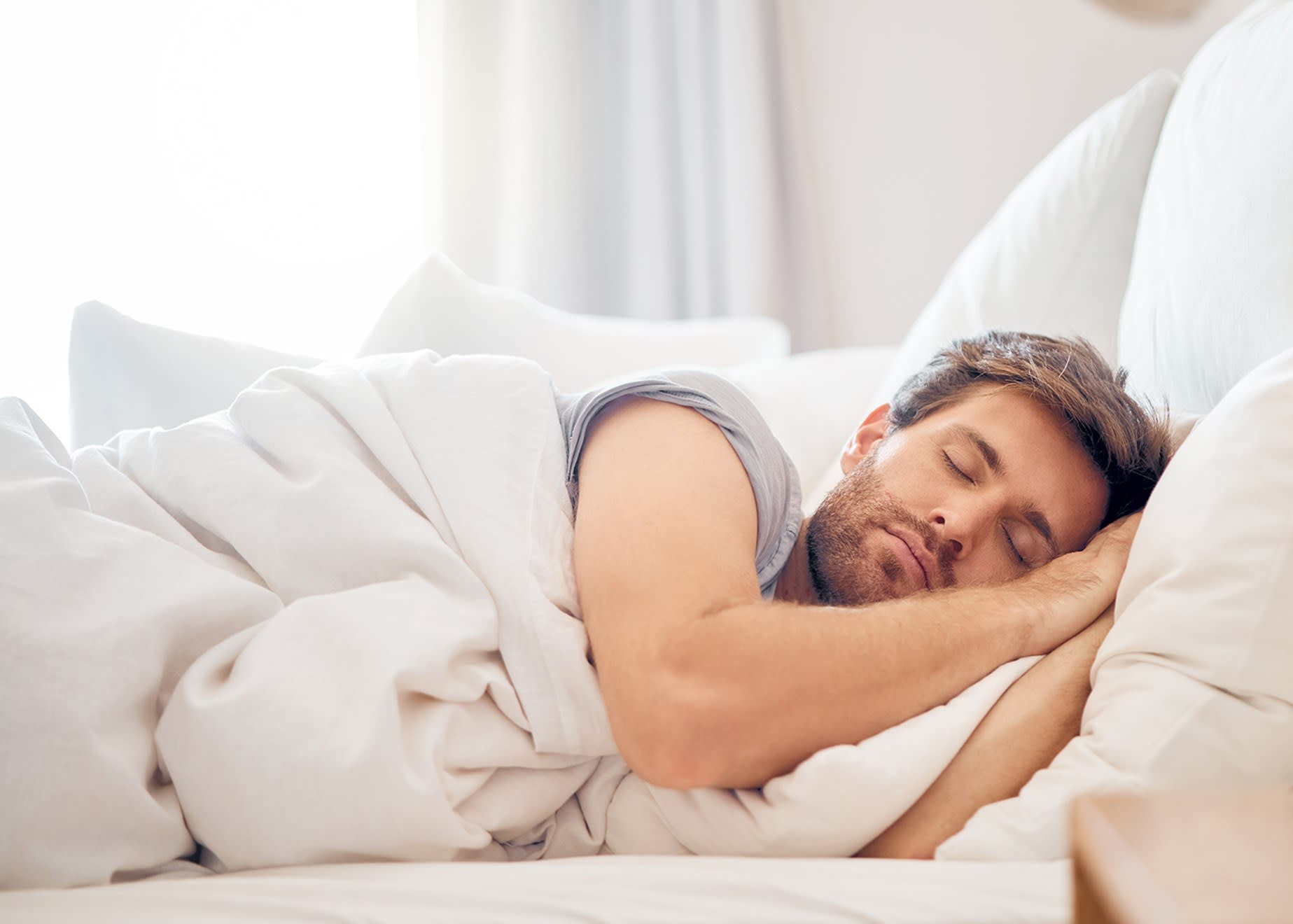 Mand der sover med hænderne under hovedet. 